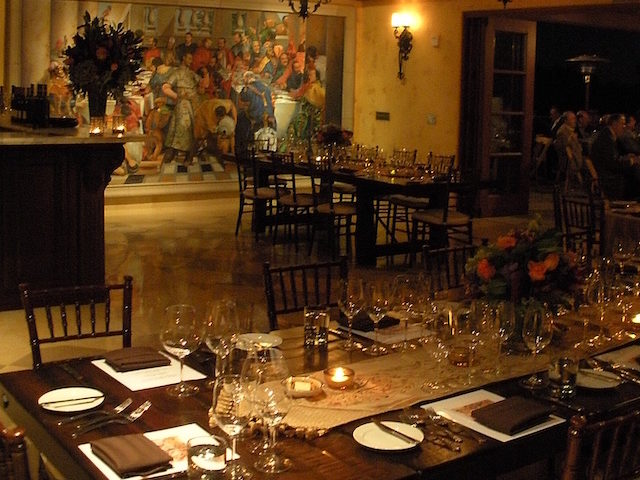 the interior of a dining space in Regale with a large mural overlooking tables set for dinner with low lighting